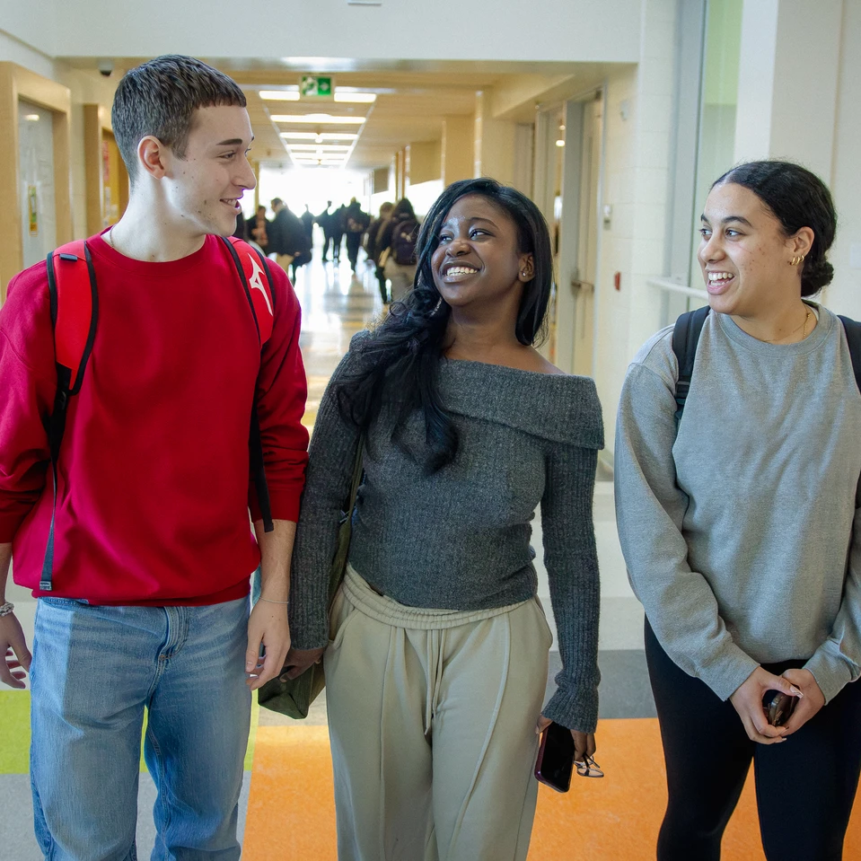 trois élèves souriants dans le corridor de l'école